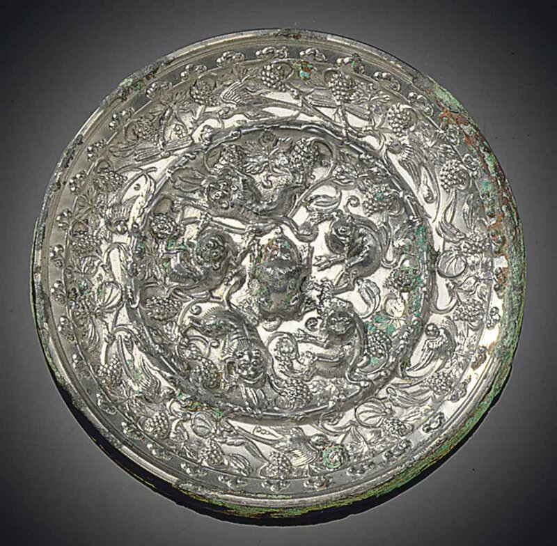 A silvery bronze 'Lion and grapevine' circular mirror, Tang dynasty (618-907)