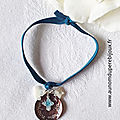 Bracelet sur ruban élastique composé d'une médaille en nacre gravée surmontée d'une mini croix émaillée et entourée d'une mini colombe en nacre et une mini étoile en nacre - 19 €