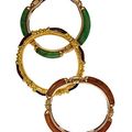 Trois bracelets joncs rigides ouvrants en or jaune ornés de segments en jade brun ou vert ou en composition noire. 