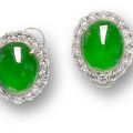 A pair of intense green oval cabochon jadeite and diamond earrings